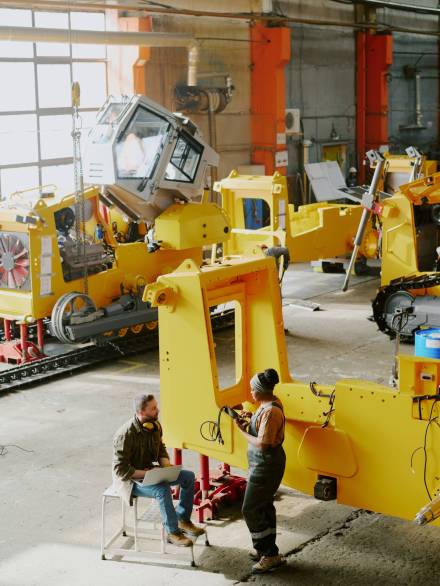 Vertical high angle view wide shot of biracial young man and woman working together at bulldozer production factory, copy space